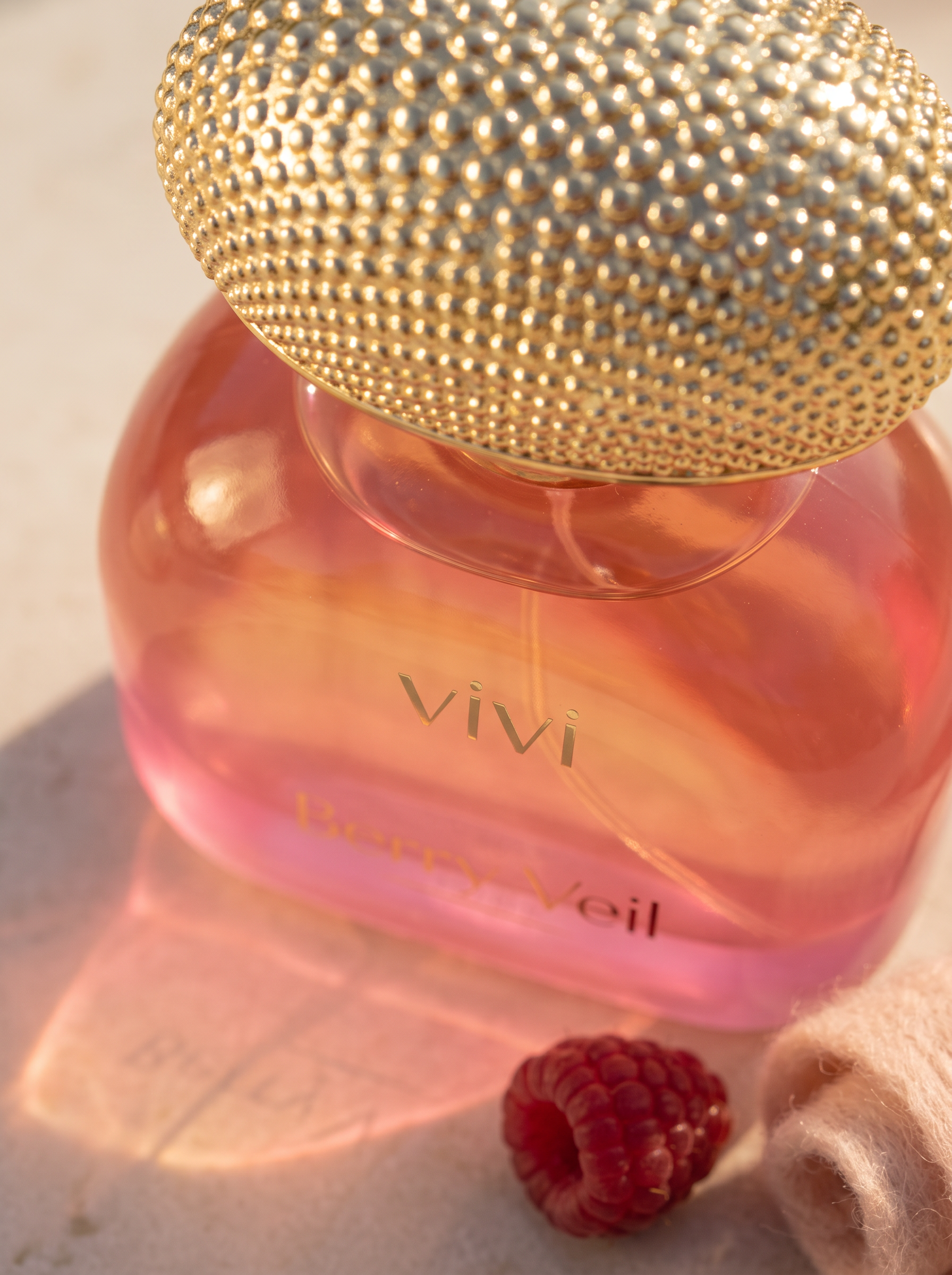 Berry Veil bottle detail — gold mesh cap and pink gradient glass close-up